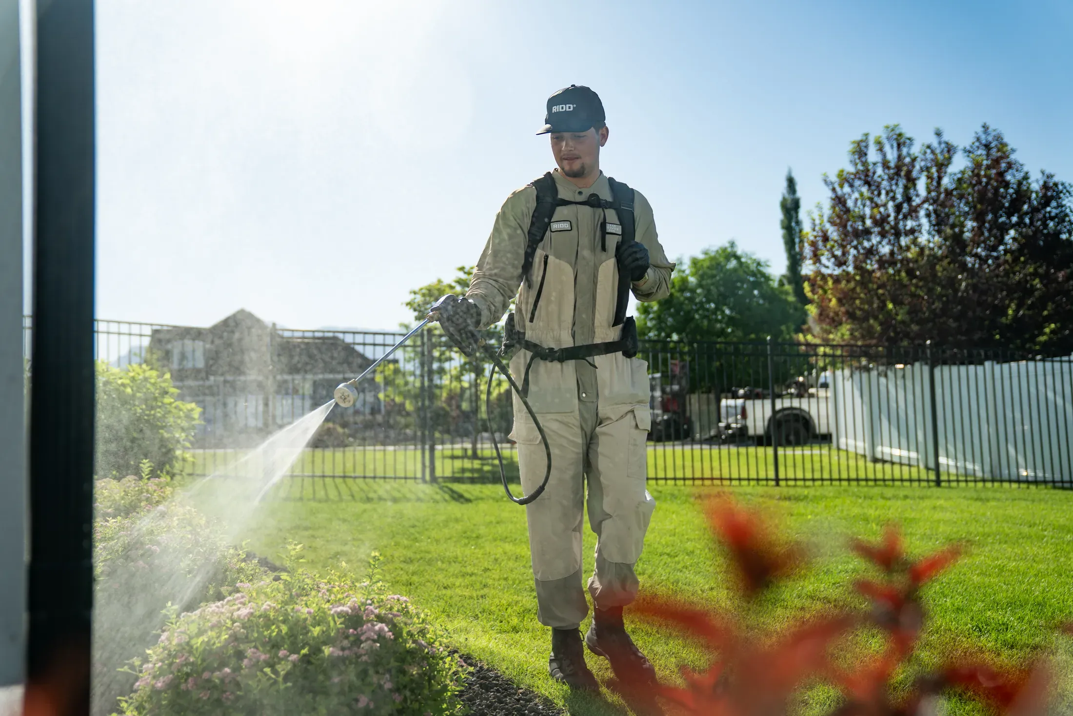 RIDD technician applying an exterior treatment across a residential lawn.