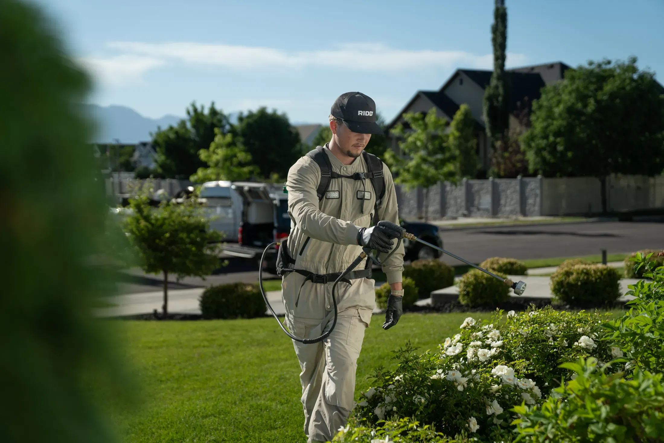 A RIDD technician treating shrubs and lawn areas during an exterior service visit.
